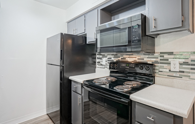 Kitchen equipped with black appliances and grey cabinets at Treehouse Apartments in Albuquerque, NM