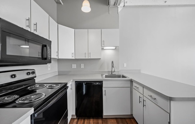 A black and white kitchen with a stove, oven, microwave, dishwasher, and sink.