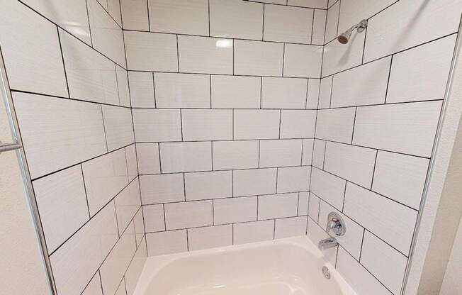 A white tiled shower with a white tub and a white door.