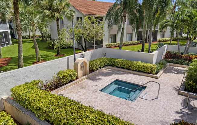 A small pool surrounded by a low wall of bushes and concrete.