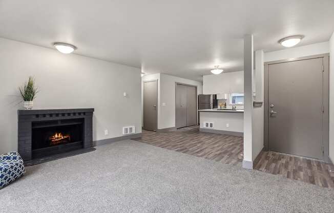 A living room with a fireplace and grey carpet.