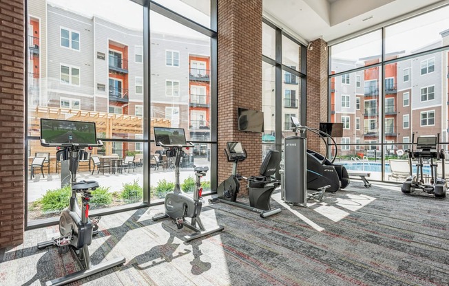 a workout room with weights and cardio equipment in a building with large windows