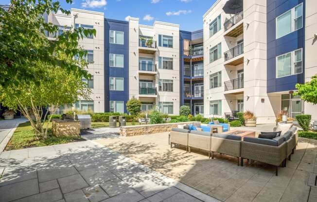 a patio with couches and a fire pit in front of an apartment building