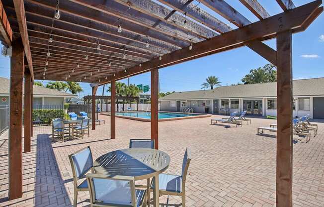 A patio with a table and chairs under a wooden pergola.