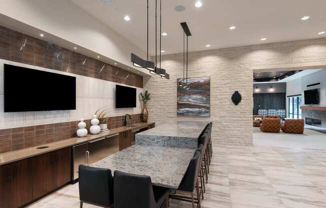A modern kitchen with a long island and black chairs.