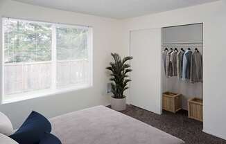 A bedroom with a bed, a wardrobe, and a plant in Redmond, WA.