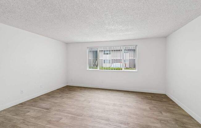 A room with a window and wooden flooring.