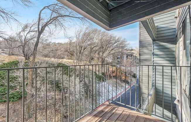 A balcony with a metal railing overlooks a river and trees.