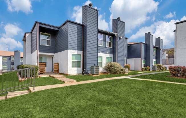 a row of townhomes with blue roofs and green grass