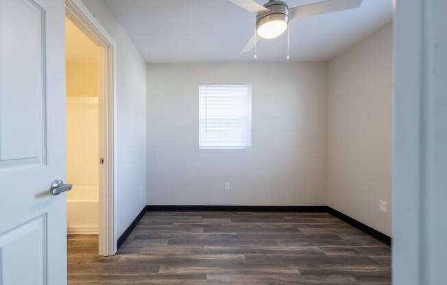 an empty room with wood flooring and a window