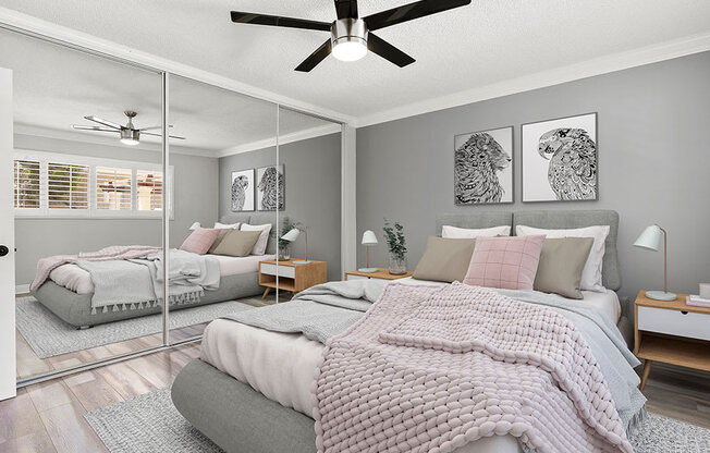 Carpeted bedroom with ceiling fan and large mirrored closet.