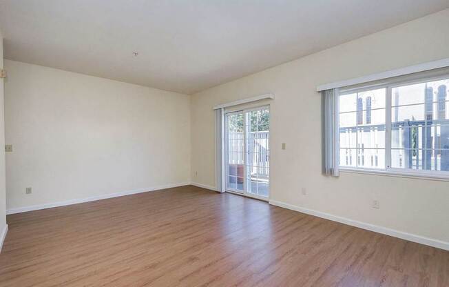 A large empty room with wooden floors and a sliding glass door.