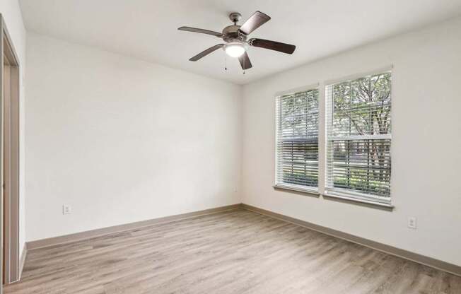 Royal Palm floor plan bedroom with a ceiling fan and a window with blinds at Oakleaf Plantation apartments in Jacksonville, FL.