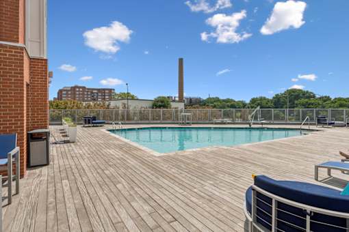 A wooden deck with a pool and a blue couch at The Waterford At Rocketts Landing Apartments, PRG Real Estate, Richmond, Virginia
