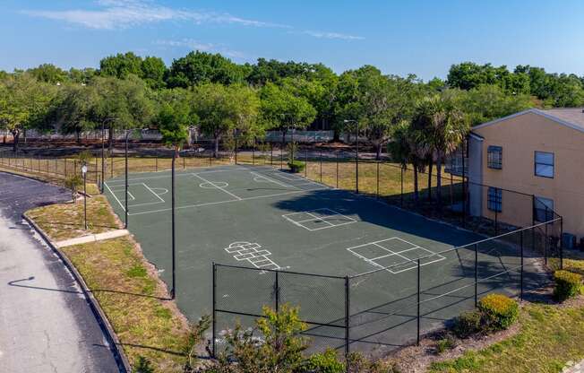 a tennis court with a fence around it next to a house