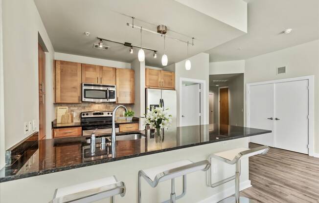 a kitchen with wood cabinetry and black countertops