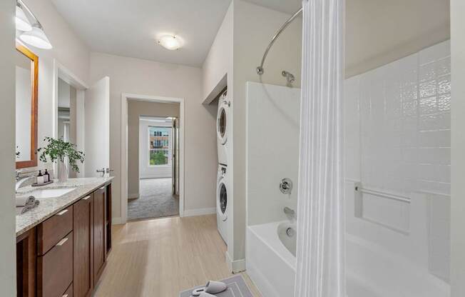 A bathroom with a white tub and a washing machine in the background.