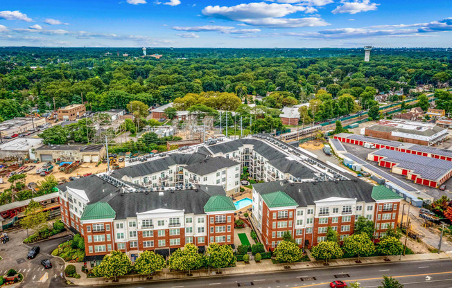 an aerial view of a large building complex with trees in the background and a blue sky with at West 130, West Hempstead, NY