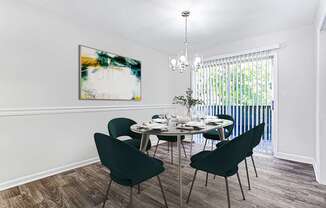 A dining room with a table set for four and a painting on the wall.