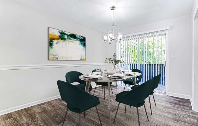 A dining room with a table set for four and a painting on the wall.