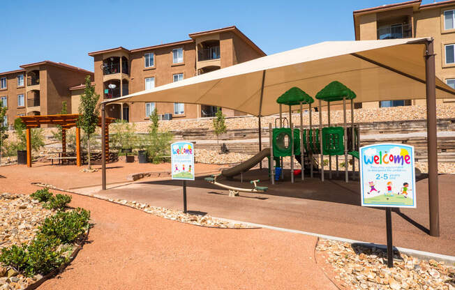 A playground area with a slide and a sign at West Park Apartments, Albuquerque