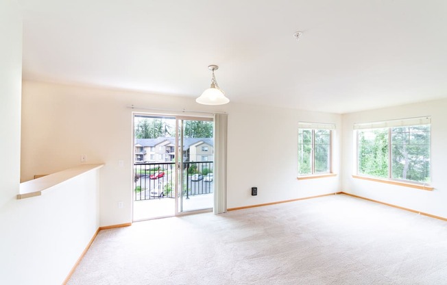 an empty living room with a sliding glass door and a balcony