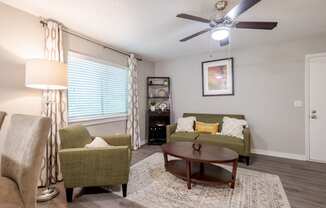 a living room with couches and a table and a ceiling fan