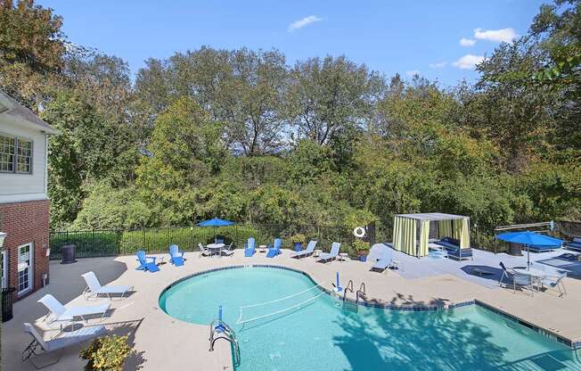 a swimming pool with chairs and umbrellas next to a house