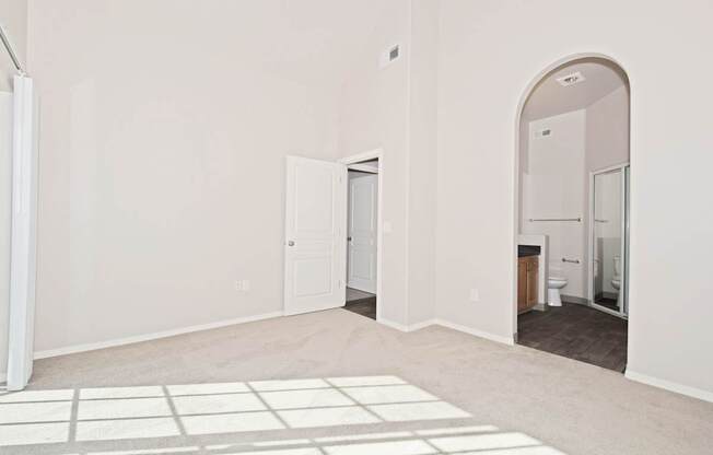 A white room with a door and a bathroom visible through the door.