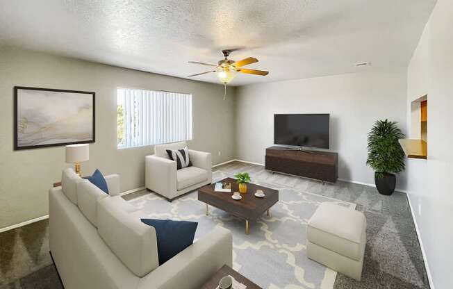 A living room with a white couch, a coffee table, a flat screen TV, and a ceiling fan.