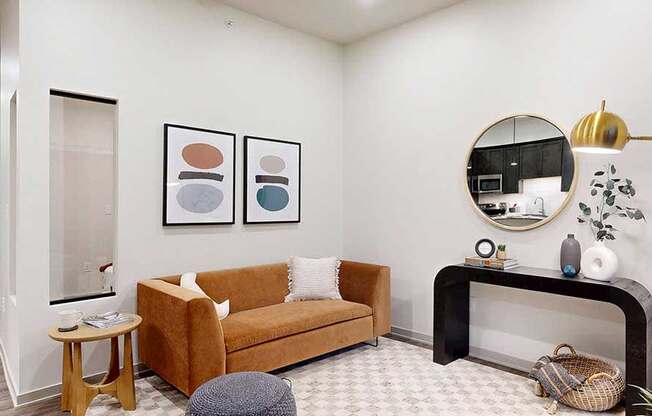 a studio living area with a sofa, chair, and modern art on the wall
