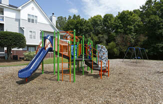 a playground with a slide and other toys in front of a house