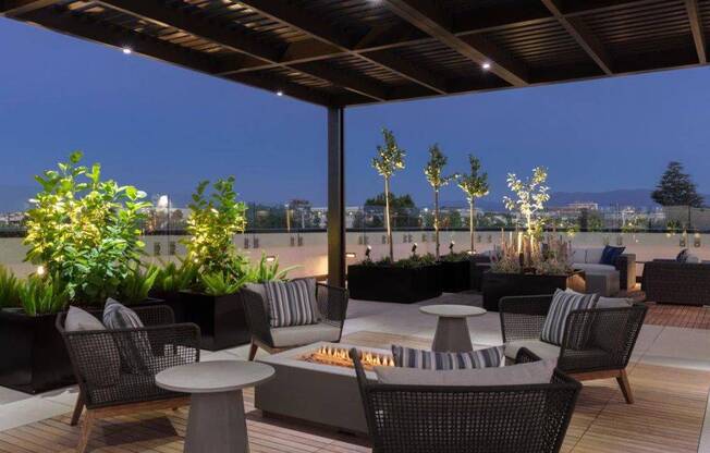 a rooftop patio with tables and chairs and a fire pit