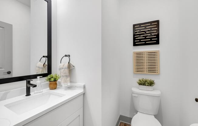 a white bathroom with a toilet and a sink at Meridian at CityPlace, Woodbury, MN