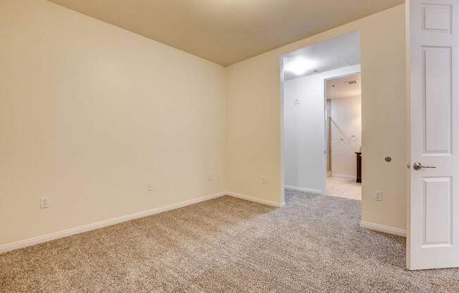A room with a carpeted floor and a doorway leading to another room.