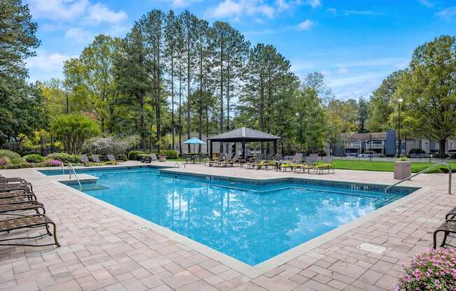 A large swimming pool surrounded by trees and a pavilion.