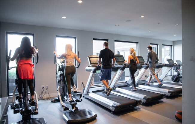 a group of people running on treadmills in a gym