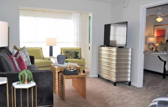 A living room with a black couch, a yellow chair, a wooden coffee table, and a television.