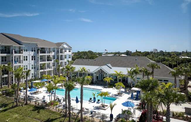 an aerial view of the resort with a swimming pool and palm trees