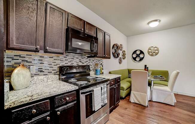 a kitchen with a stove top oven next to a table with a green couch in the background