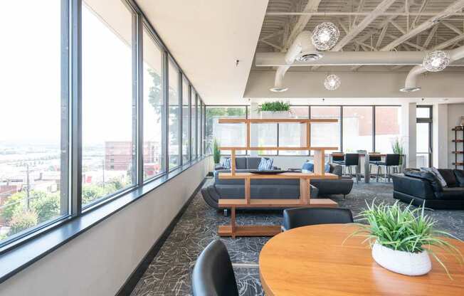 A modern office space with a long wooden table and black chairs.