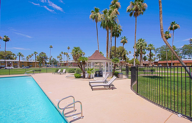 a pool with a gazebo and palm trees in the background