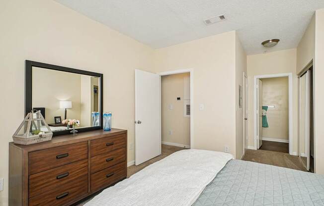 A bedroom with a bed, dresser, mirror, and two doors.