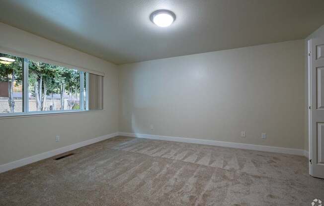 an empty living room with carpet and a window