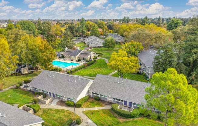 Elevated drone shot of the Pinecrest exterior community. Single story buildings with the blue swimming pool area in the distance. at Pinecrest Apartments, California