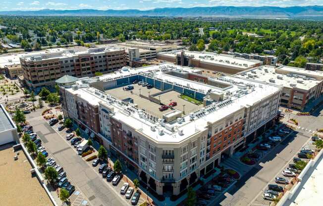 an aerial view of a large building with a parking lot in the middle of it
