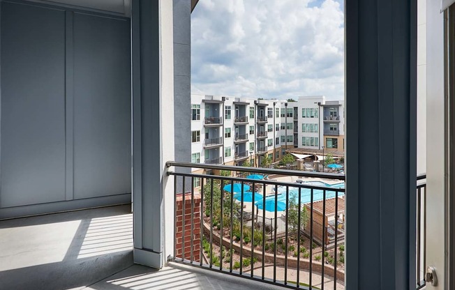 A balcony with a view of a pool and buildings.