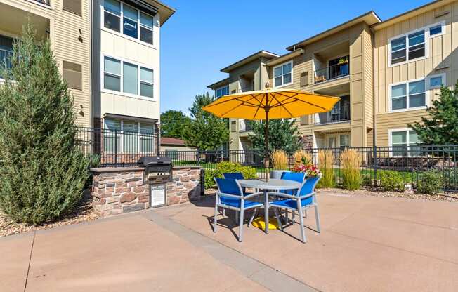 a patio with a table and chairs and an umbrella in front of an apartment building