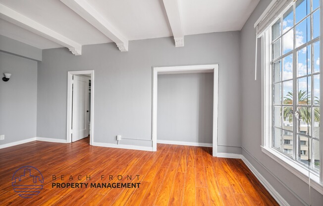 an empty room with wood flooring and large windows