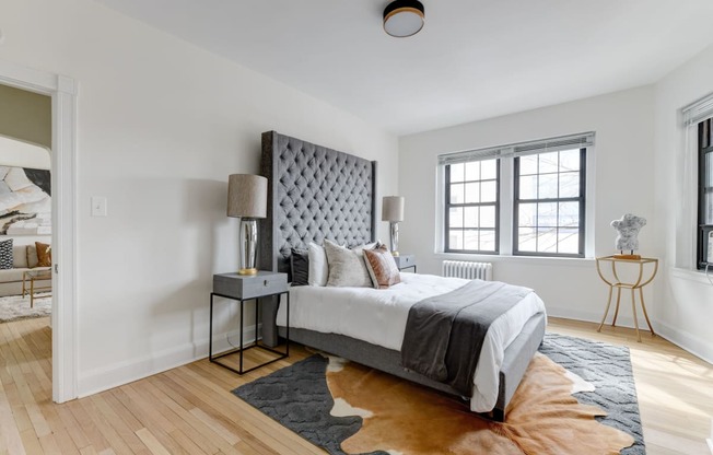 bedroom with bed, nightstand, large windows and hard wood floors at the dahlia apartments in washington dc